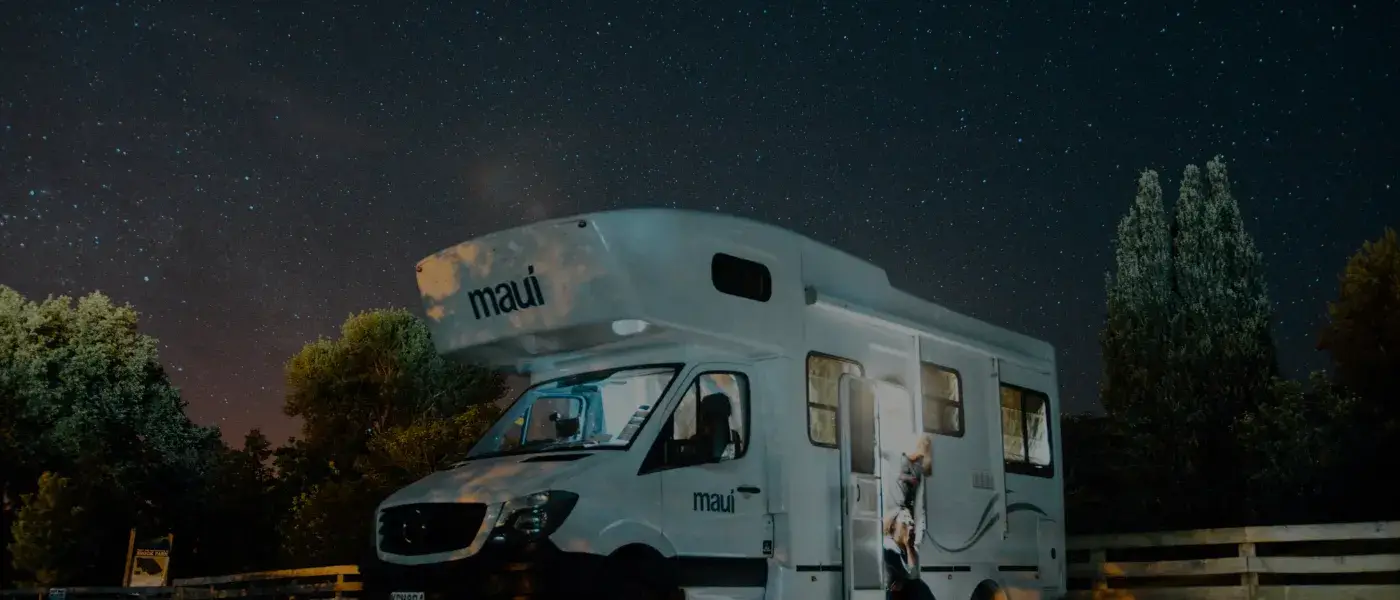 A brightly lit RV under the star covered sky